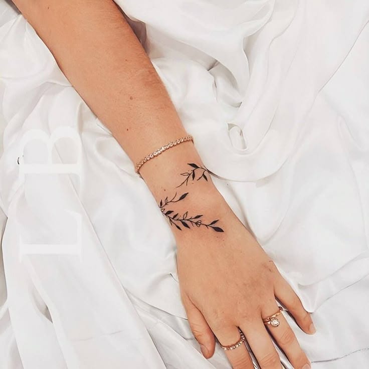 Delicate botanical artistry wraps around the wrist like nature's own jewelry, creating an enchanting bracelet effect that flows seamlessly with the hand's natural curves. The fine linework and organic placement make this leafy design feel effortlessly integrated into the skin, while the minimalist black ink allows the intricate leaf details to truly shine ✨