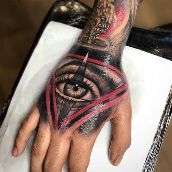 Bold geometric lines slice through shadow and light, creating a mesmerizing hand piece where a piercing eye becomes the centerpiece of an angular masterpiece. The striking contrast between deep blacks and vivid red accents transforms this hand into a living canvas that commands attention with every gesture 👁️