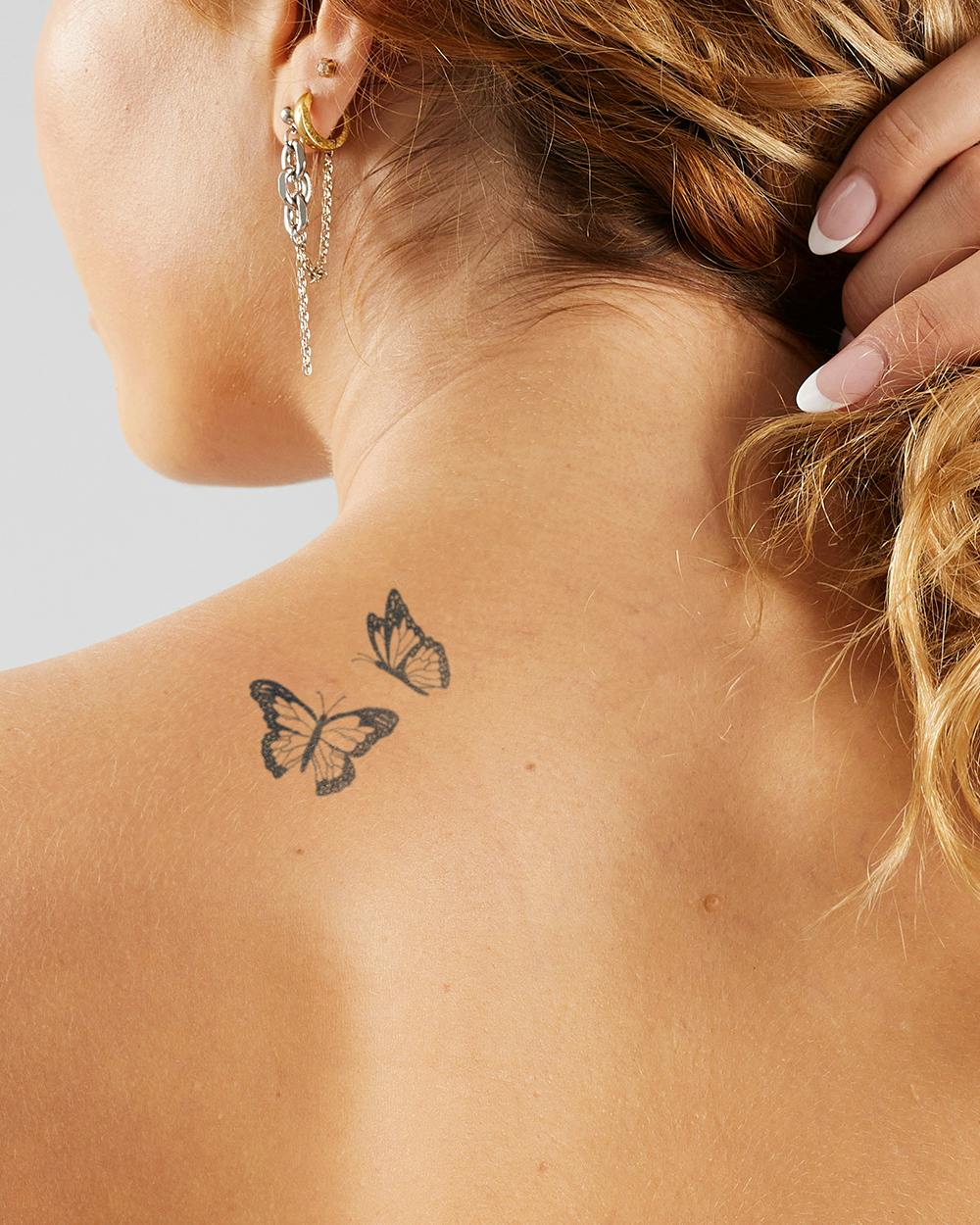 Delicate monarch butterflies dance across sun-kissed skin in this dreamy neck tattoo that perfectly captures nature's grace in motion. The fine line work and strategic placement behind the ear creates an enchanting peek-a-boo effect that's both subtle and striking 🦋 Paired with those gorgeous chain earrings, this ink transforms the neck into a canvas of feminine artistry.