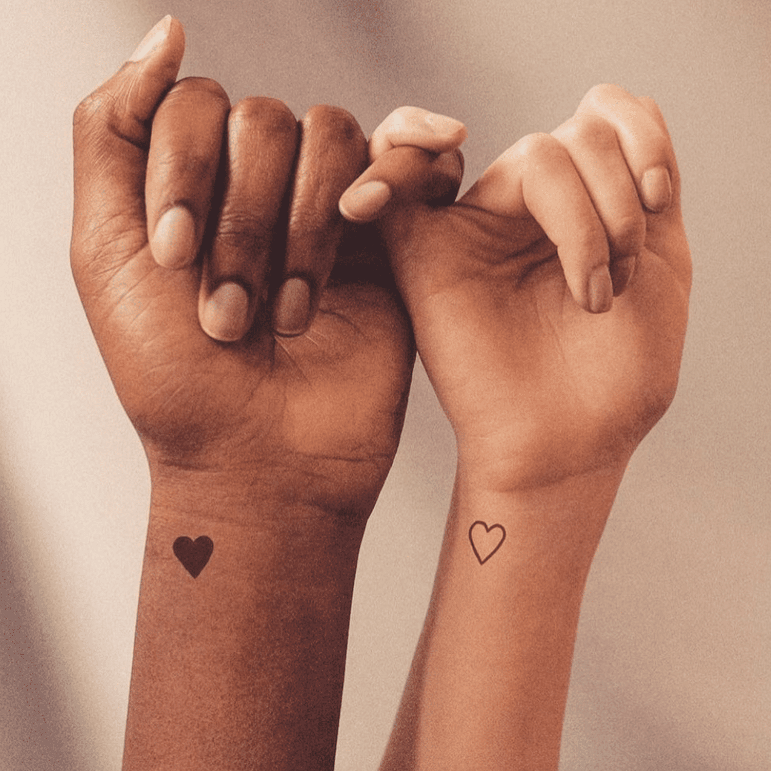 Two hands reach toward each other, each adorned with a delicate heart tattoo that tells a story of connection and unity. The contrast between the solid black heart and outlined heart creates beautiful visual balance, while their placement on the inner wrists makes this matching design both intimate and meaningful ✨ Perfect for couples, best friends, or anyone celebrating the bonds that matter most.