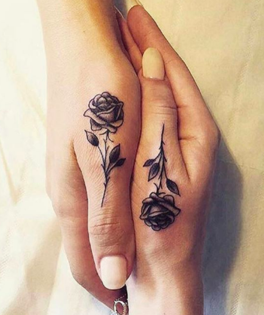 Complementary roses bloom across two fingers, creating a romantic matching tattoo that tells a complete story when hands come together 🌹 The delicate black ink work features stunning contrast between the full blooms and trailing stems, perfectly sized for this intimate finger placement. A beautiful symbol of connection that literally brings two people together with every touch.