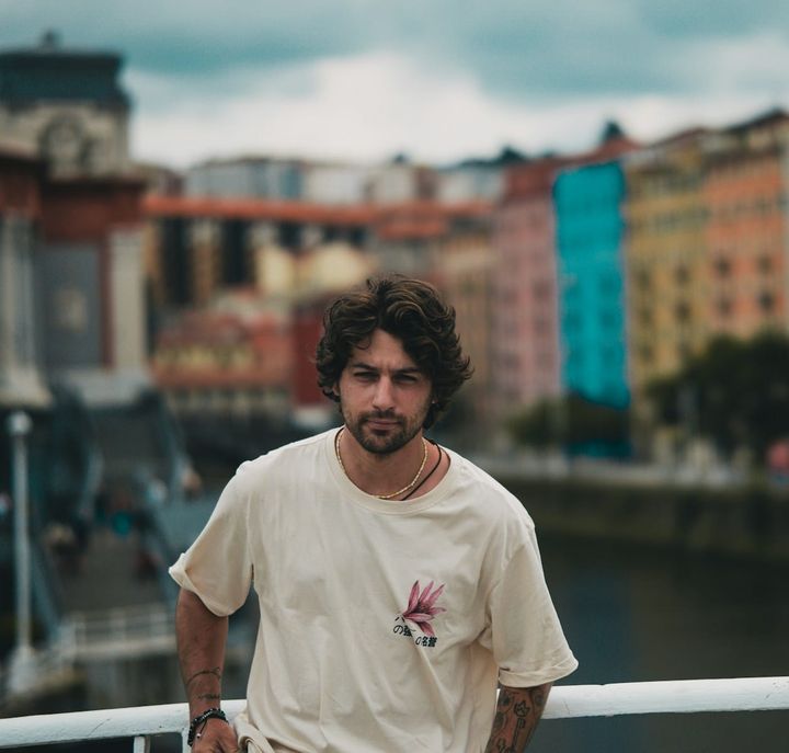 A man standing on a bridge next to a body of water
