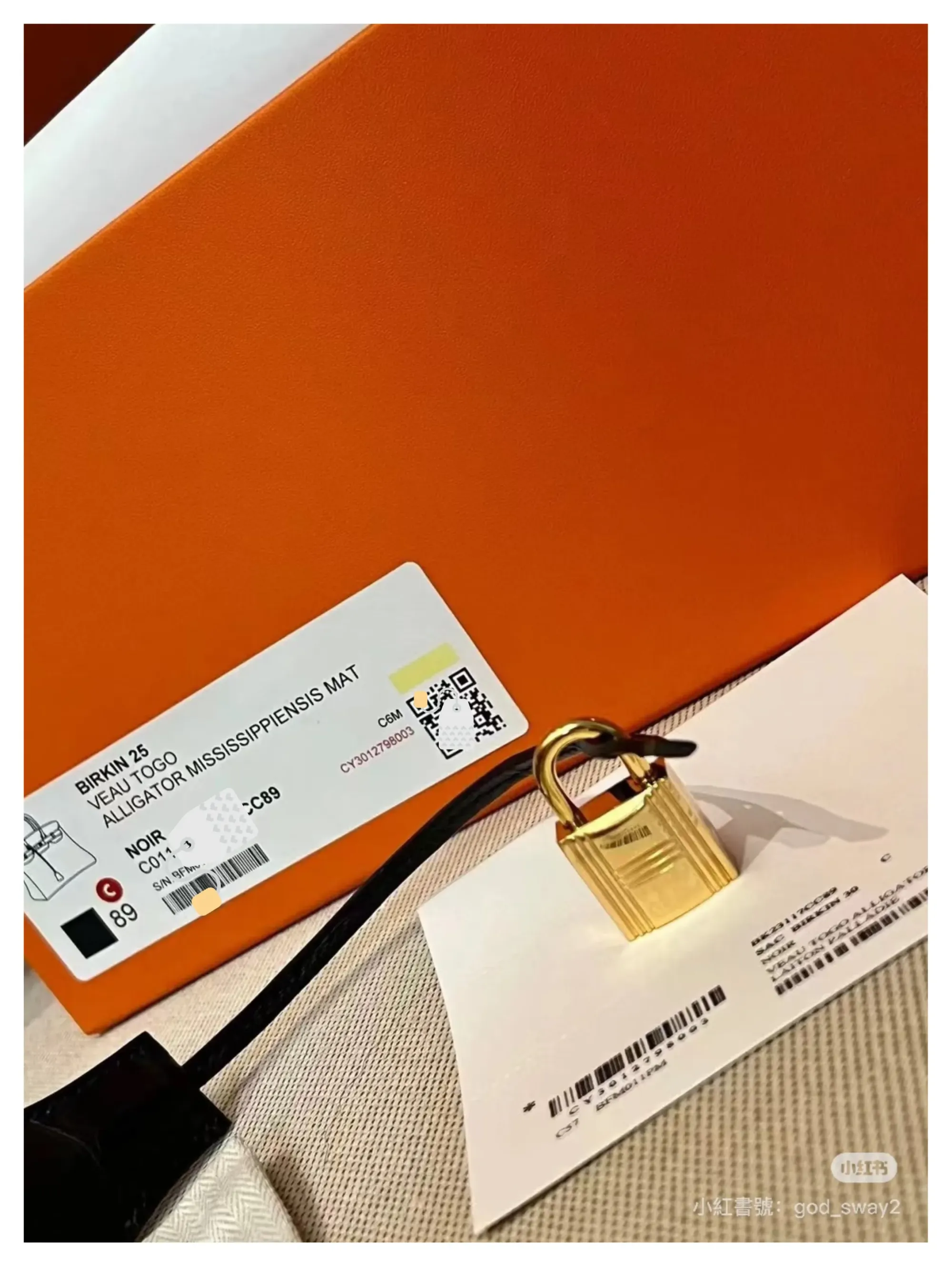 Hermès 橙色盒外產品標籤示例,顯示 Birkin 25、皮質(Alligator Mississippiensis Mat)、顏色 Noir(#80)、序號及 QR Code 等資訊。