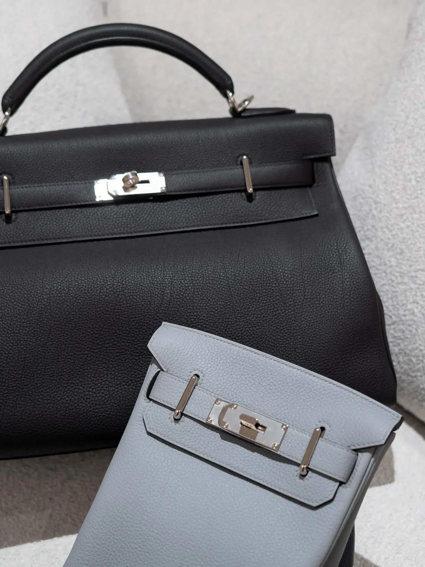 Hermès Kelly Maxi 42（Noir）與&nbsp;HAC a Dos PM（Gris Pantin）對比展示，一深一淺形成鮮明對比，突顯經典黑色嘅穩重感與&nbsp;Gris Pantin&nbsp;冷灰調嘅輕盈層次。