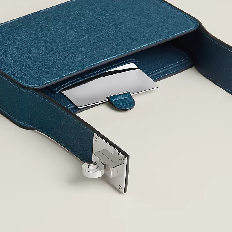 Sanglons Clutch 設計以 Birkin、Kelly 經典 sanglons 皮帶結構為靈感,將 strap 與 Touret 旋轉扣比例放大,集中呈現於袋面,整體線條簡潔,強調結構與金屬細節。