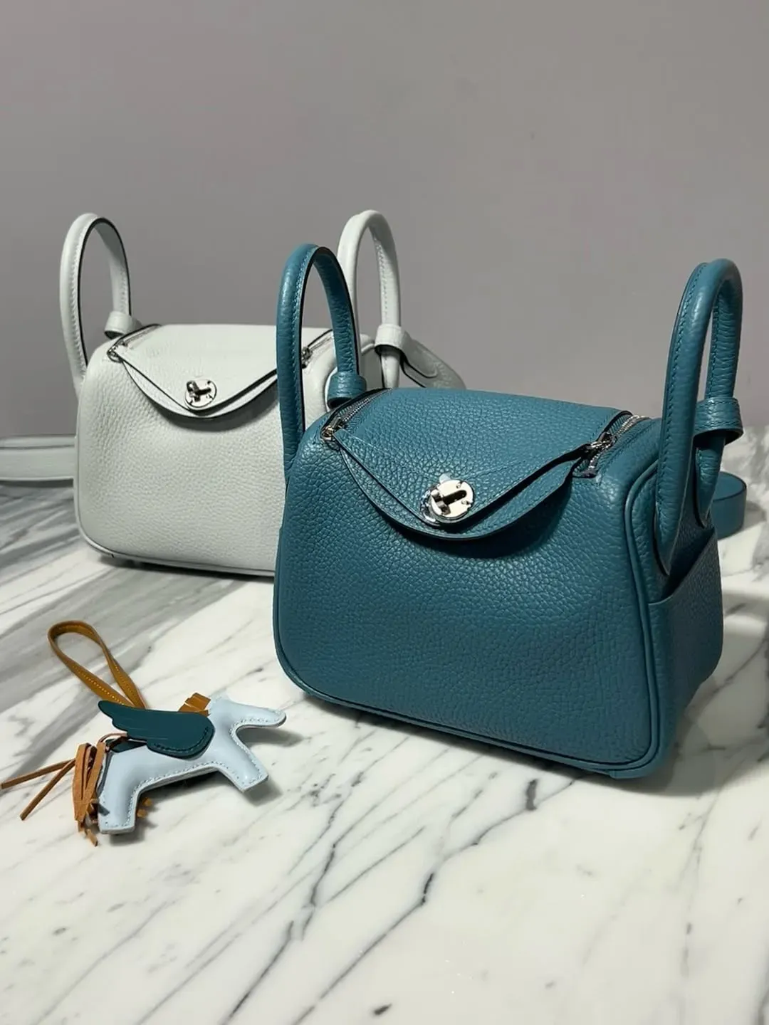 兩個 Mini Lindy 並排展示,前者採用 Blue Jean Clemence 皮革配銀扣。相同袋型配搭唔同色號,更容易比較色彩呈現、皮革質感,以及 Blue Jean 嘅休閒牛仔藍風格。