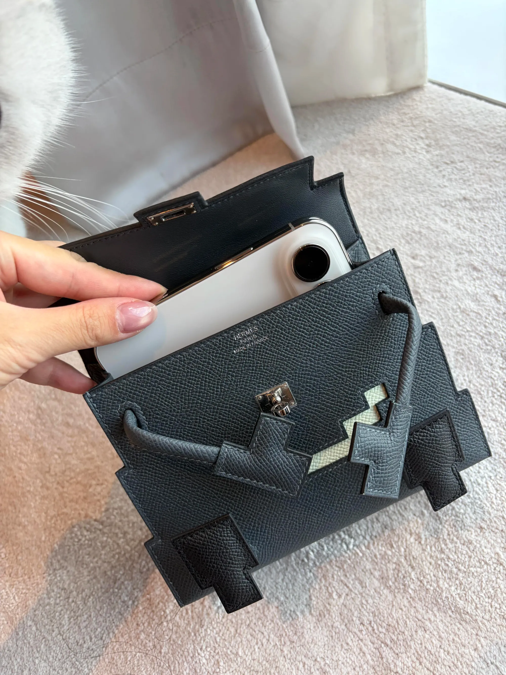 網民實測 iPhone Duo 摺合後放入 Hermès Kelly Doll Picto,展示手機與迷你手袋嘅尺寸配搭。