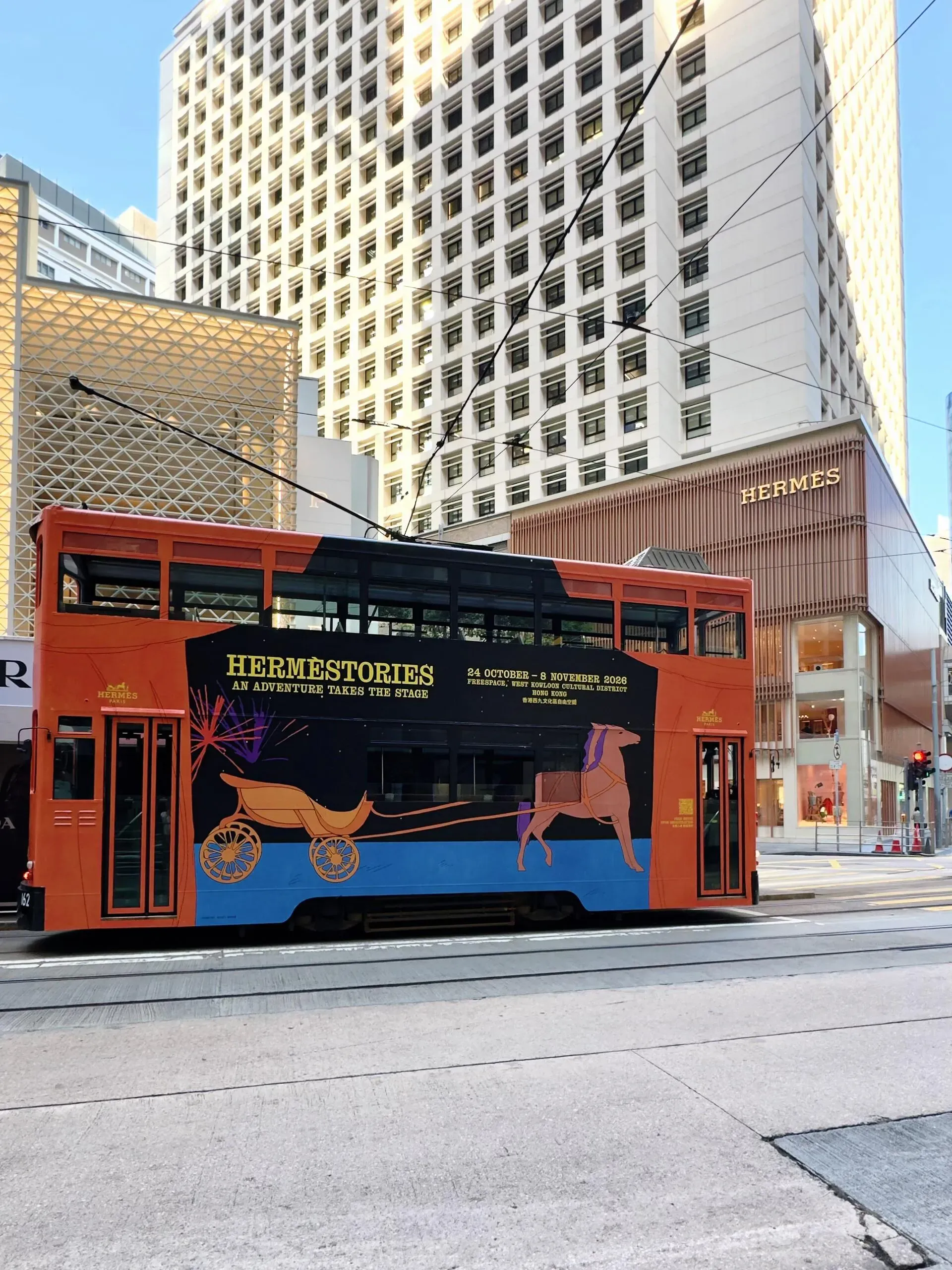 愛馬仕(Hermès)主題叮叮車駛經中環太子大廈分店門口,車身設計用作宣傳西九文化區嘅大型品牌歷史展覽。