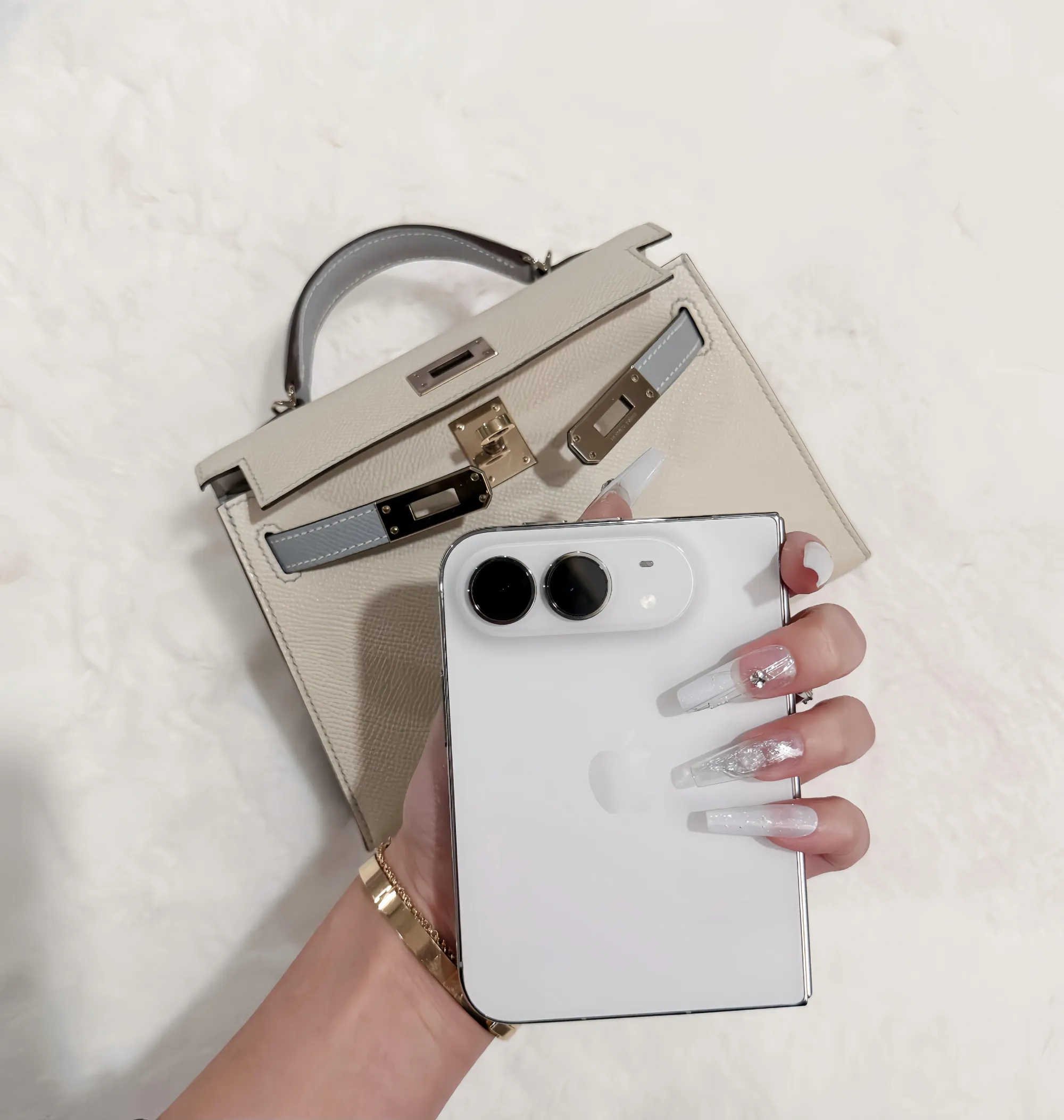 iPhone Duo 與 Hermès Mini Kelly 20 II 手拎合照,展示摺疊手機與迷你手袋嘅外觀比例。