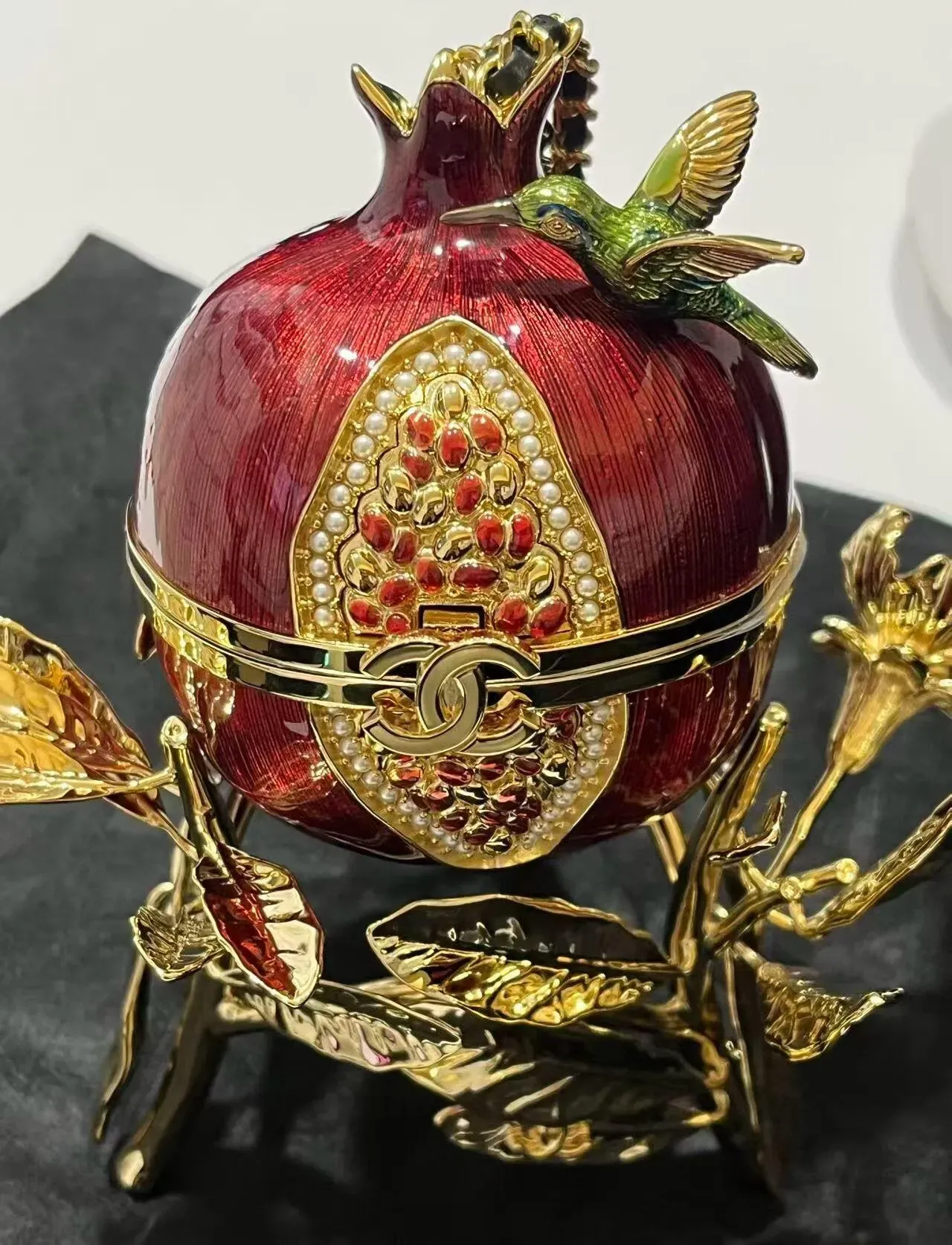 石榴造型晚宴包加入立體蜂鳥及多色裝飾，為紅色果實輪廓增添自然元素與視覺層次。