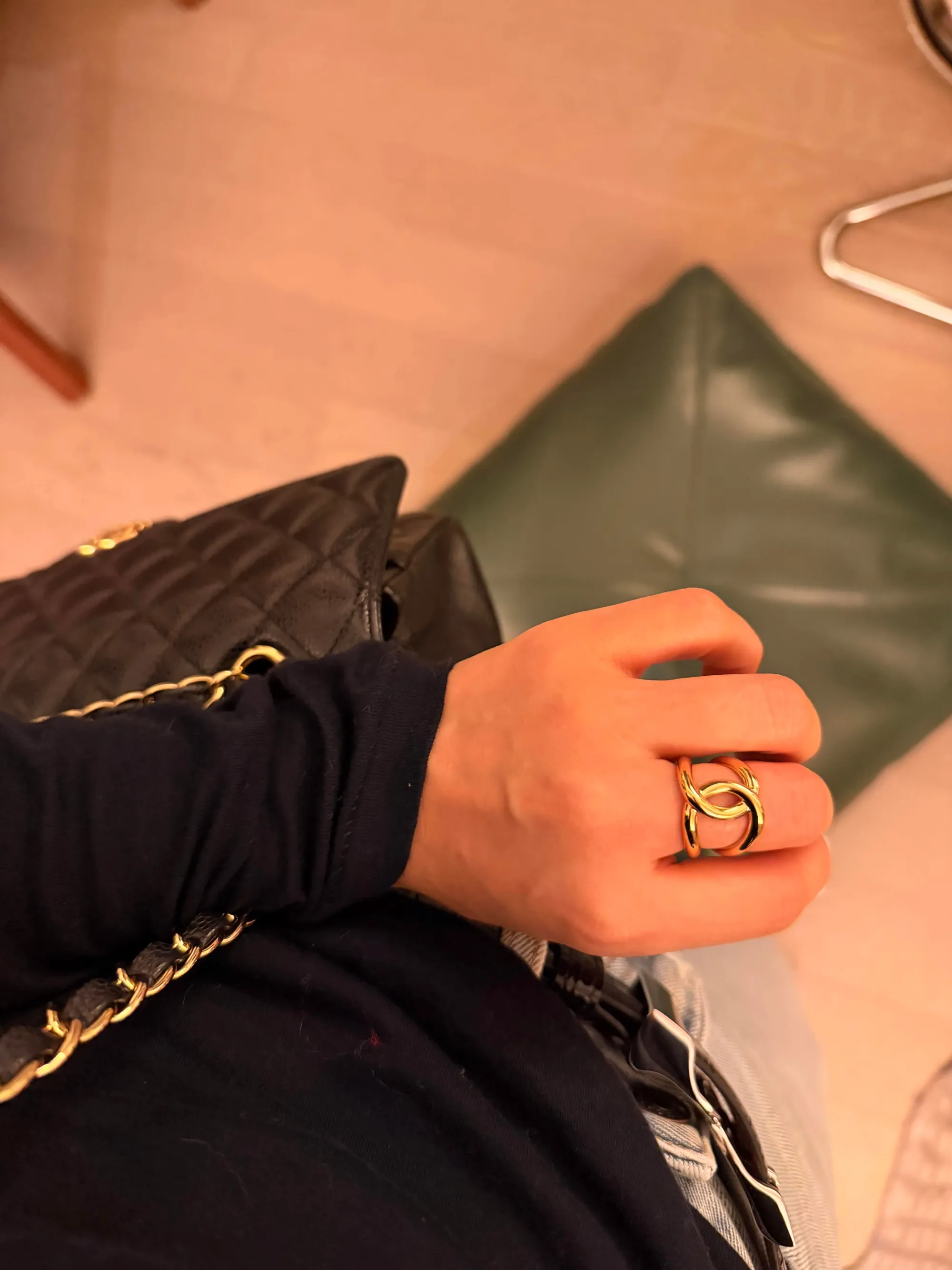 金色雙C戒指上手近照,可見弧形戒身及交疊C形線條,金屬表面反光令戒指輪廓更加突出。