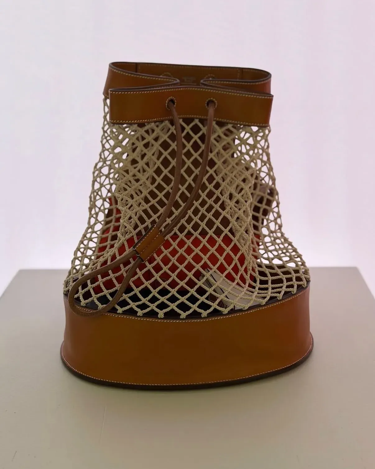 網民分享Fishnet Bucket Backpack實物圖，可見魚網式袋身結構及皮革包邊，袋口以皮革抽繩收緊，背帶則採用繩索設計。