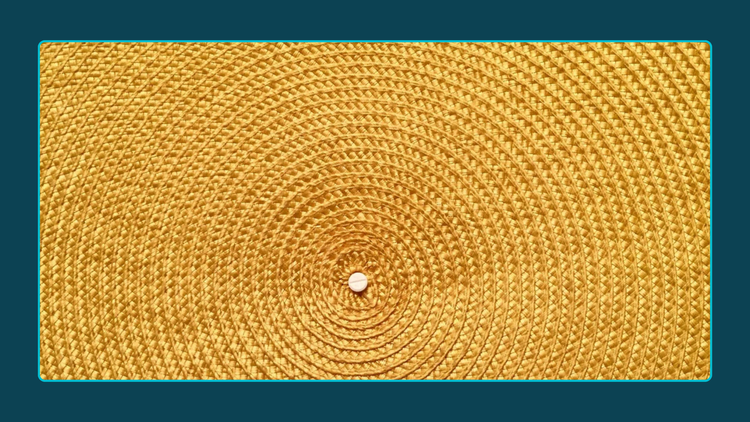 Close up photograph of yellow basket woven in circles around a central node. 