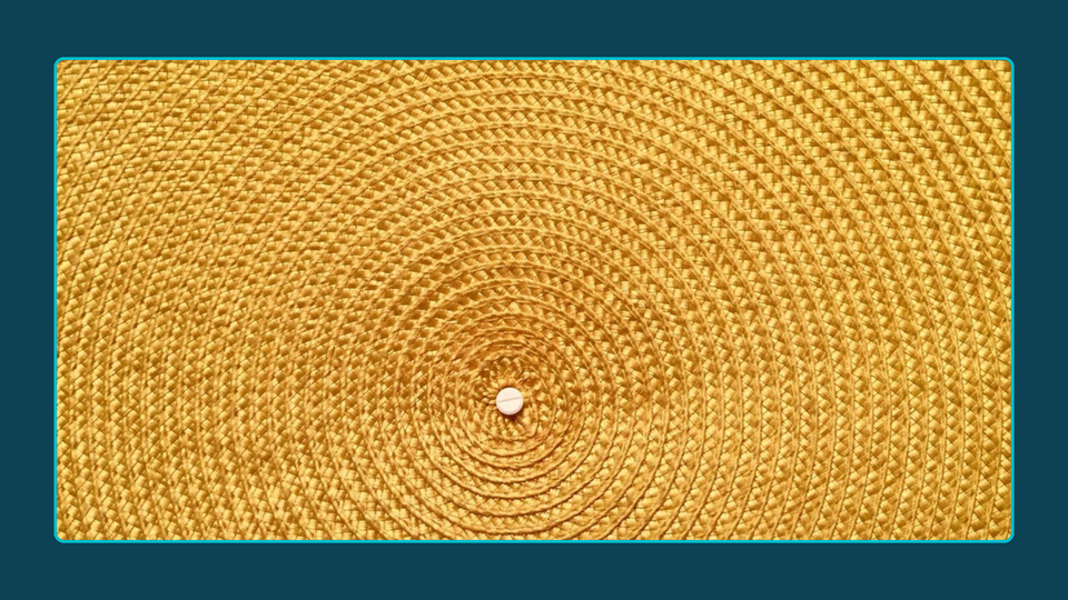 Close up photograph of yellow basket woven in circles around a central node. 