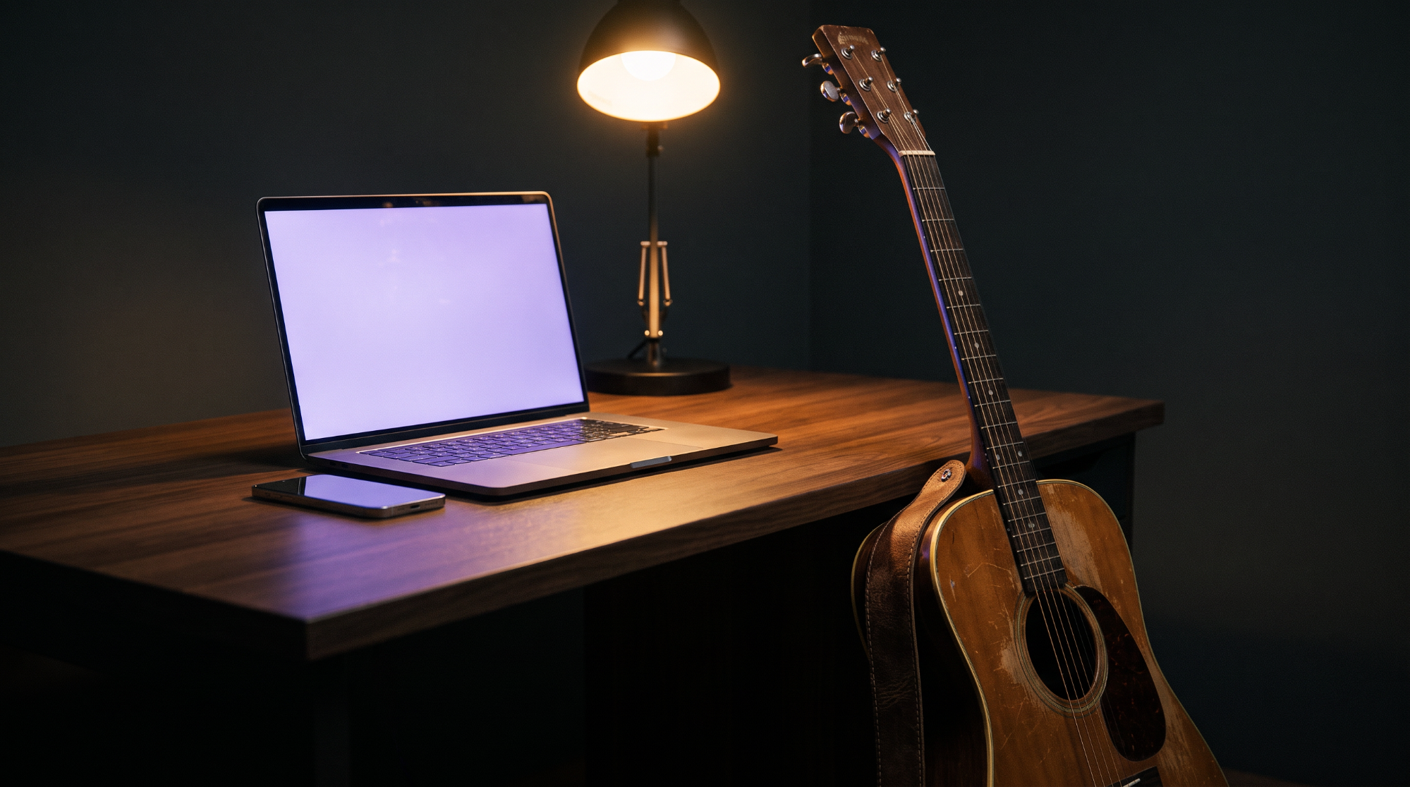 In-body image option B: a laptop, phone, and acoustic guitar on a desk at night