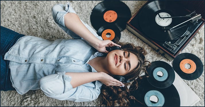 young woman surrounded by vinyl records as she discovers new music