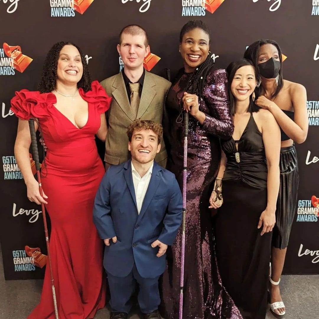 RAMPD team members at the 65th annual GRAMMYs. Six people smiling in front of GRAMMYs backdrop