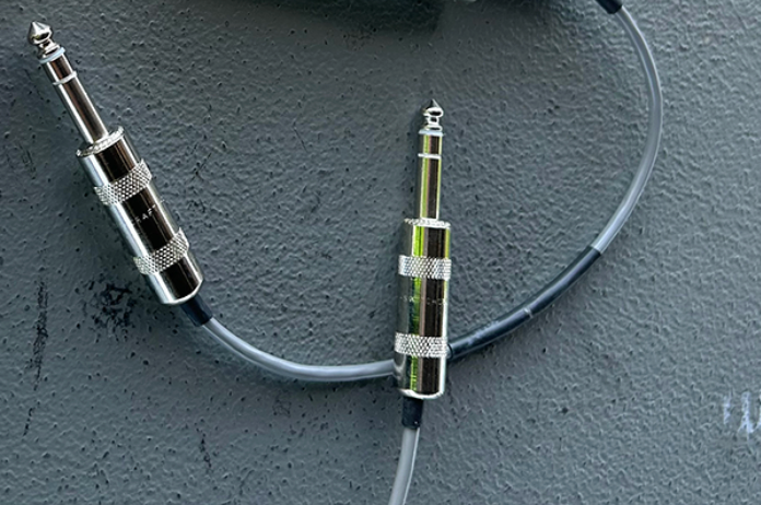 A screen grab of a quarter-inch TRS cable is pictured in a grey background with silver endings