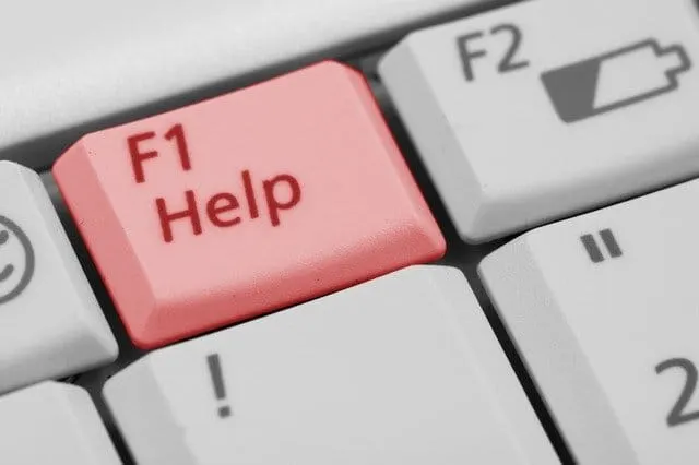 F1 Help key on computer keyboard, close-up of emergency support button for technical assistance.