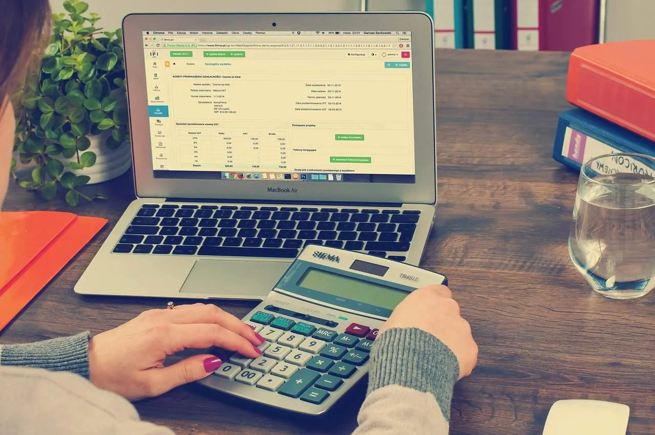 Tax calculation on laptop with calculator for business expenses.