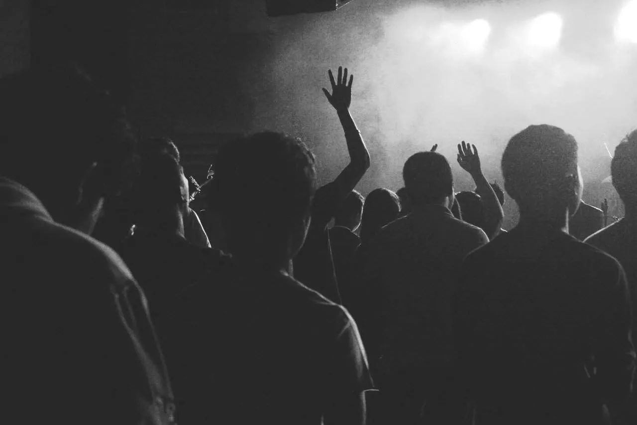 Crowd at a music concert or live event, raising hands and enjoying the show, black and white photo, energetic audience experi