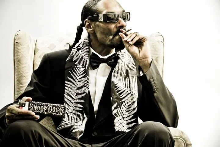 Luxury music executive wearing virtual reality glasses, smoking, holding a remote control, dressed in a tuxedo with a pattern