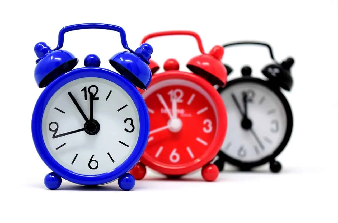 Bright blue, red, and black vintage alarm clocks showing different times, symbolizing deadlines, urgency, and timely updates