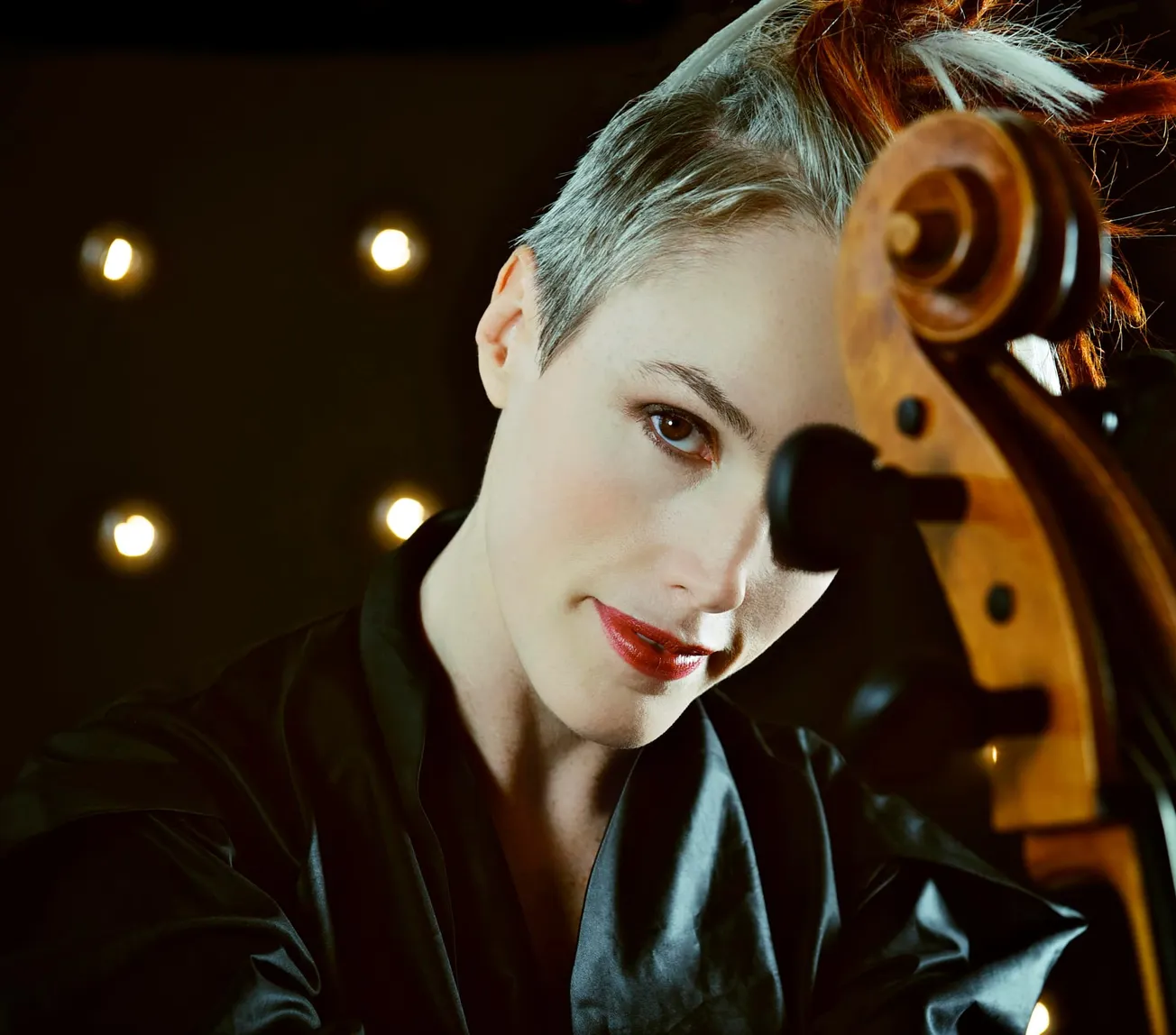 Stunning woman with short gray hair and red lipstick holding a violin, intimate music scene, indoor setting with warm lightin