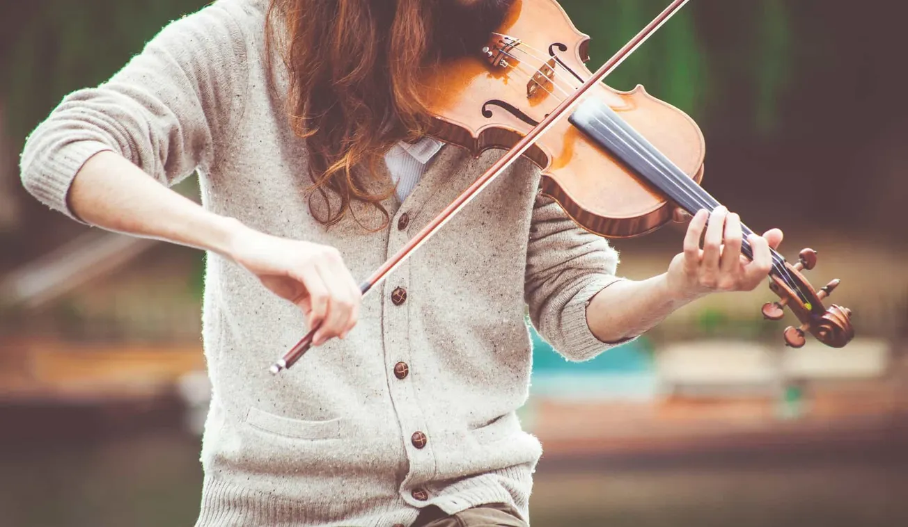 Vibrant woman playing the violin outdoors, showcasing musical passion and skill, with a blurred natural background perfect fo