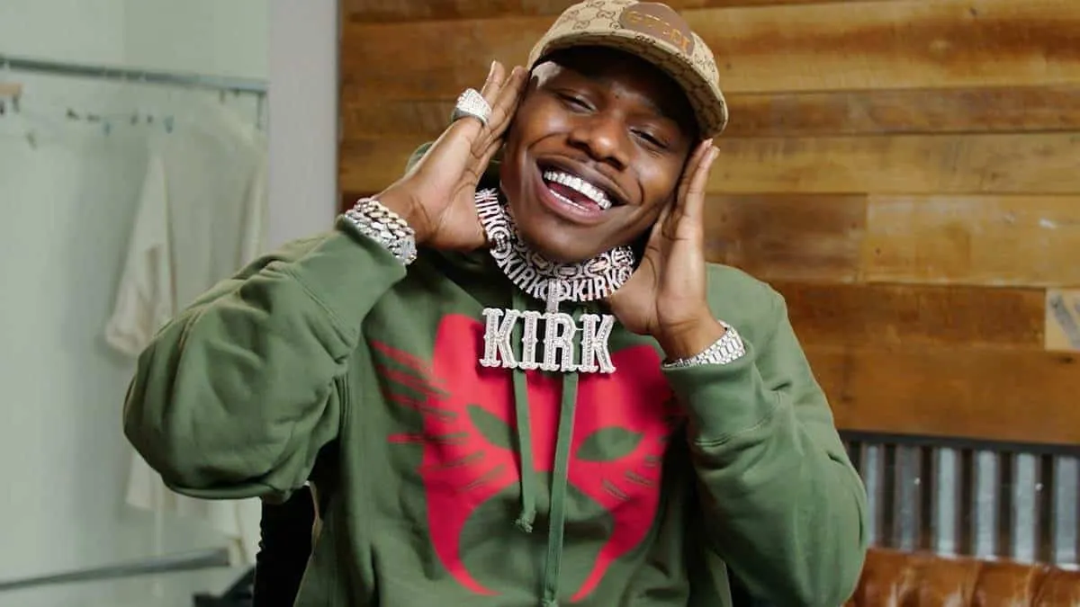 Vibrant image of a smiling young man wearing jewelry, a cap, and a green hoodie with a red graphic, showcasing a lively and e