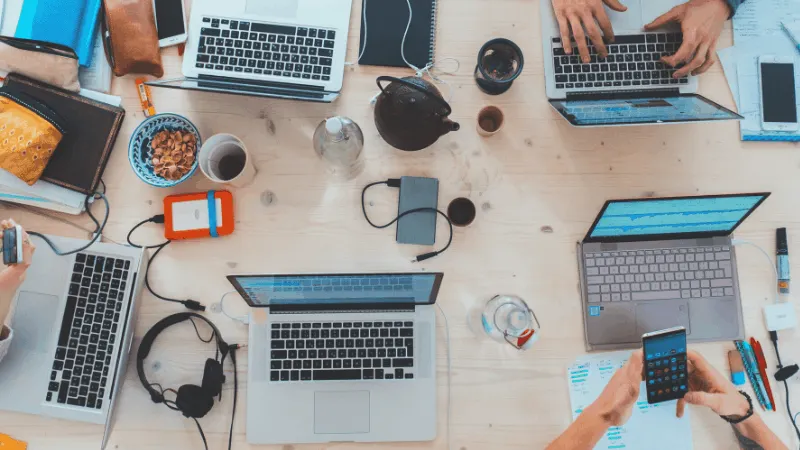 Laptops, smartphones, and office supplies on a wooden desk highlighting digital music marketing, streaming platform managemen