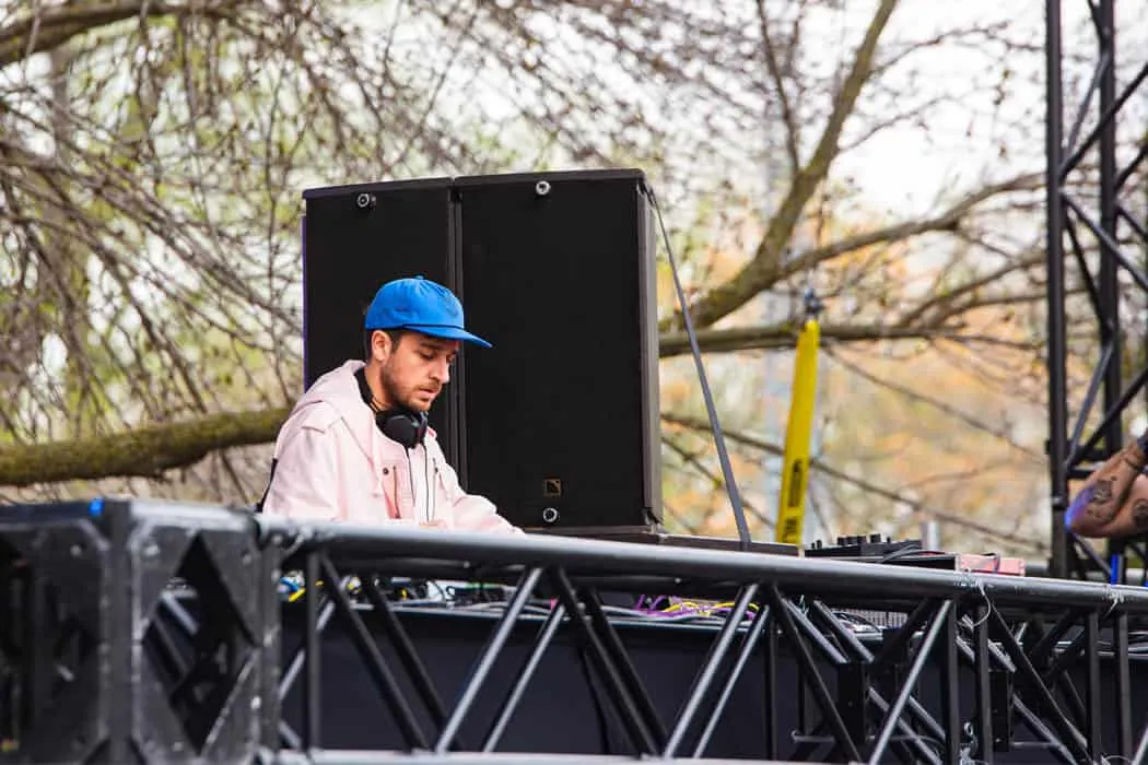 DJ performing at outdoor music event with trees in background, showcasing live music, DJ culture, outdoor festivals, and elec