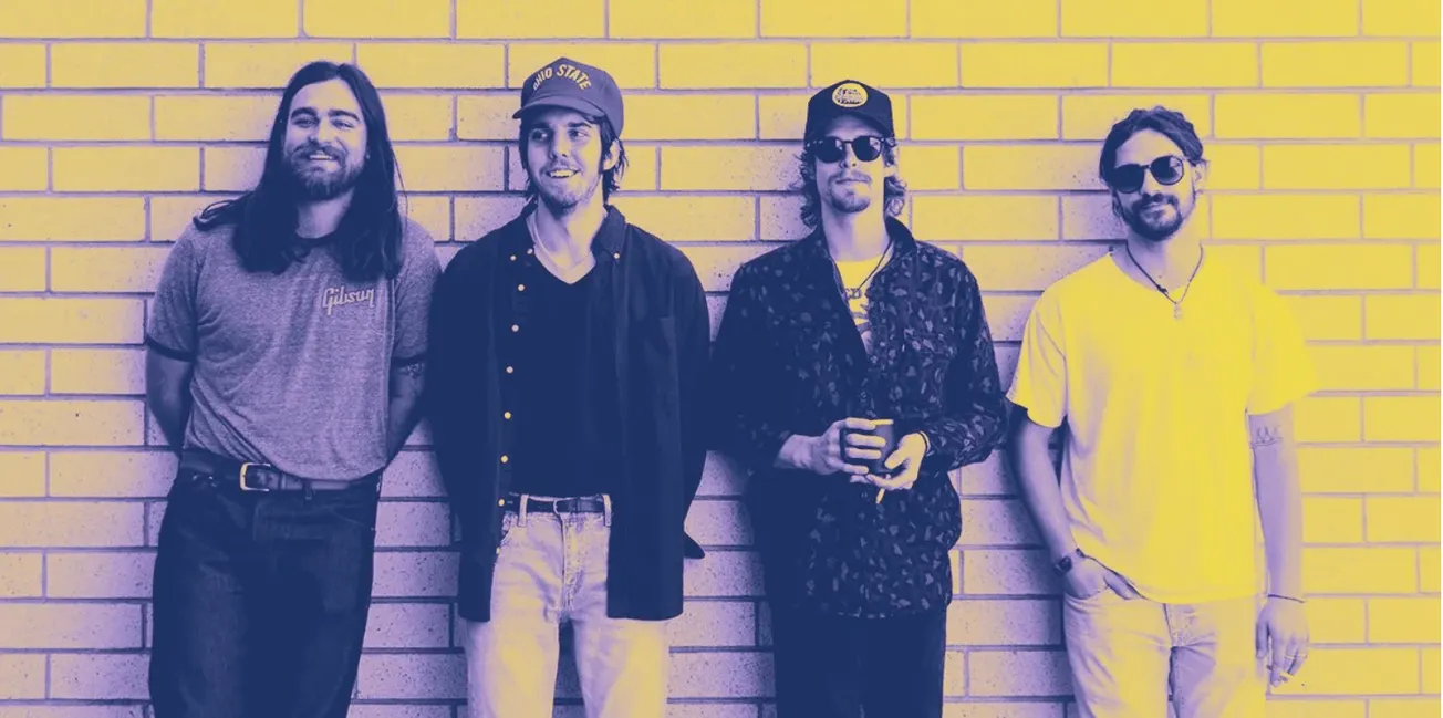 Young indie band members standing against brick wall, relaxed music scene, casual style, vibrant atmosphere, modern musicians