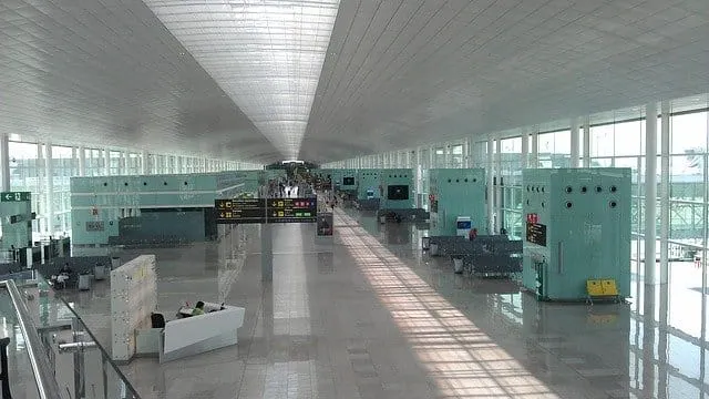 Bright modern airport terminal with high glass walls, spacious seating areas, and check-in counters, showcasing travel, airpo
