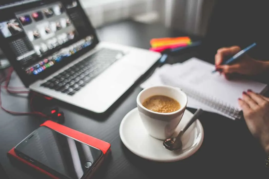 Fast-paced creative workspace with laptop, smartphone, coffee cup, and notebooks, ideal for music industry professionals, con