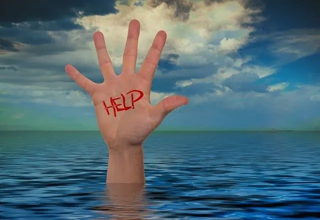 A hand reaching out above water with "HELP" written on the palm, symbolizing a plea for assistance amidst a water emergency.
