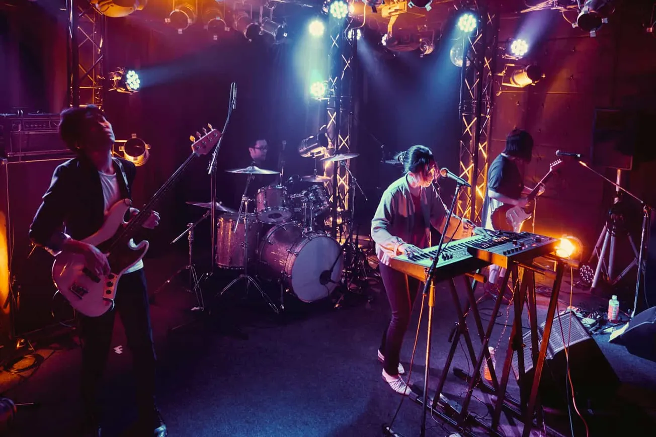 Vibrant live band performance on stage with colorful lighting and musical instruments including guitars, drums, and keyboard