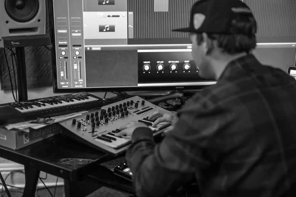 Creating a new music track in a professional recording studio with a digital audio workstation, synthesizer, and mixing conso