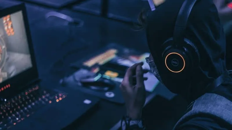 A person wearing headphones working at a laptop with music production equipment, highlighting digital music creation, DJing,