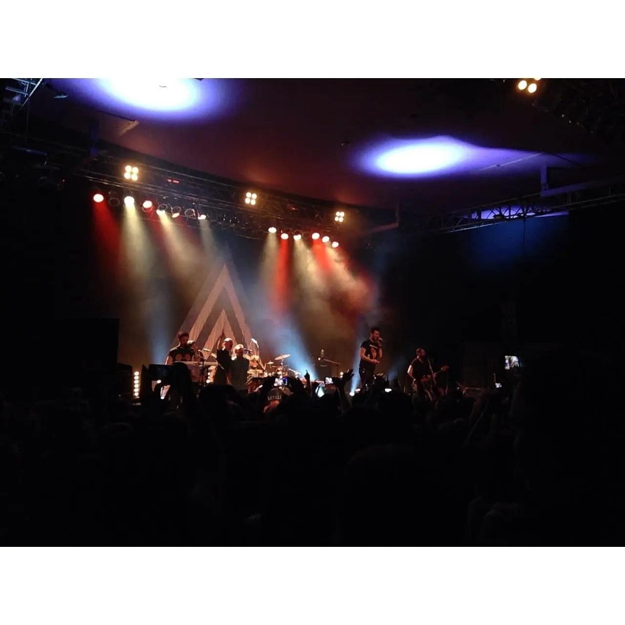 Vibrant live concert scene with band performing on stage under colorful lights, engaging audience with music, showcasing mode