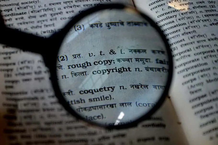 Rough copy definition, copyright in dictionary, dictionary page magnified through a magnifying glass, detailed view of words