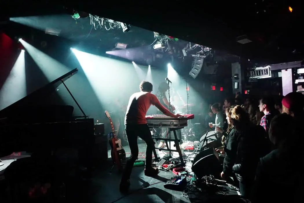 Keyboardist performing live concert at indoor music venue with audience, stage lighting, and sound equipment - vibrant music