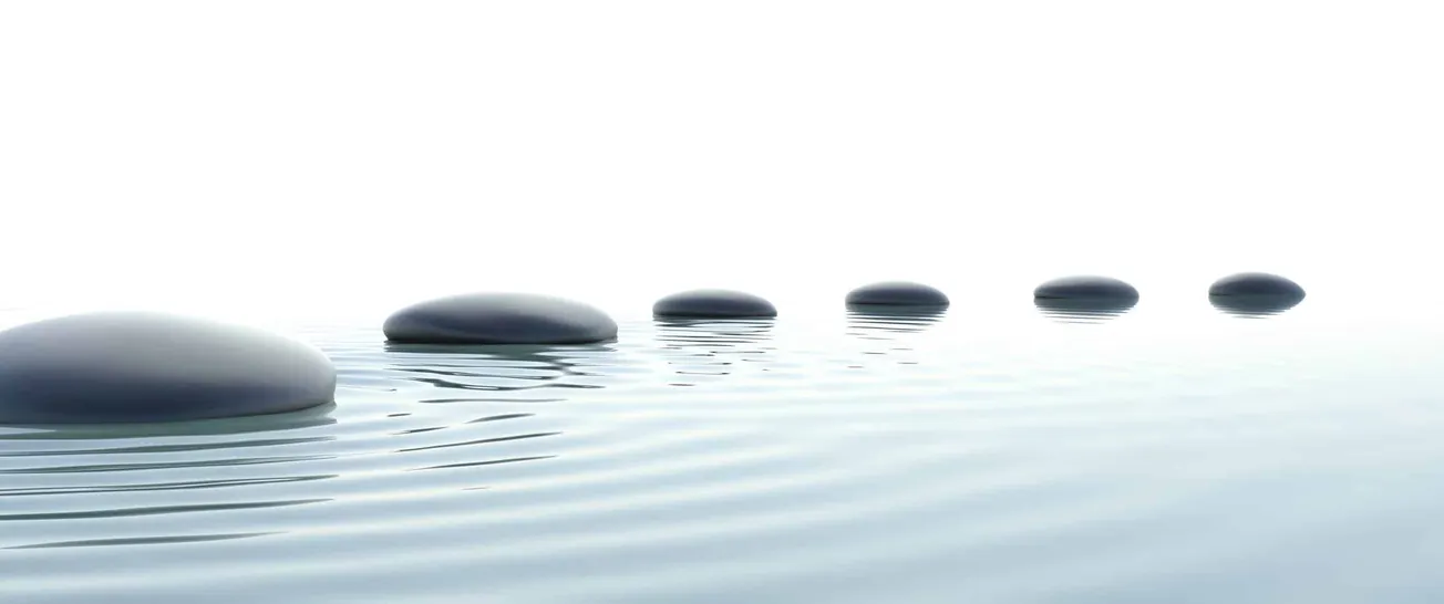Smooth black stones floating on calm water with subtle ripples, minimalist zen landscape representing tranquility and balance