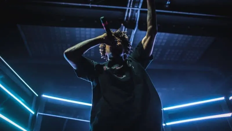 Vibrant live music performance with a singer holding a microphone under colorful stage lighting.