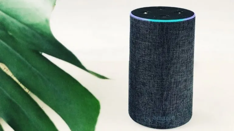 Amazon Echo smart speaker with fabric design on a white surface, activated with blue ring light, emphasizing smart home techn