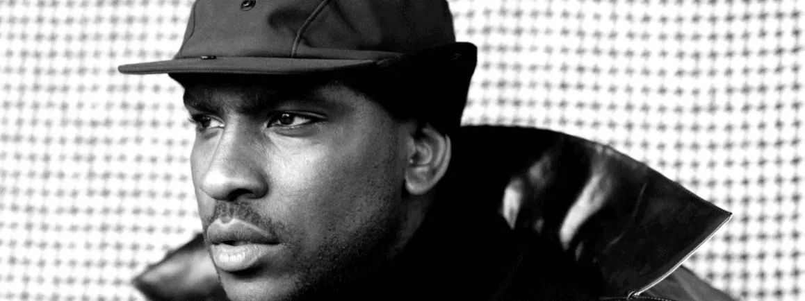 Young man in stylish black leather jacket and baseball cap, close-up portrait, modern urban fashion, artistic black-and-white