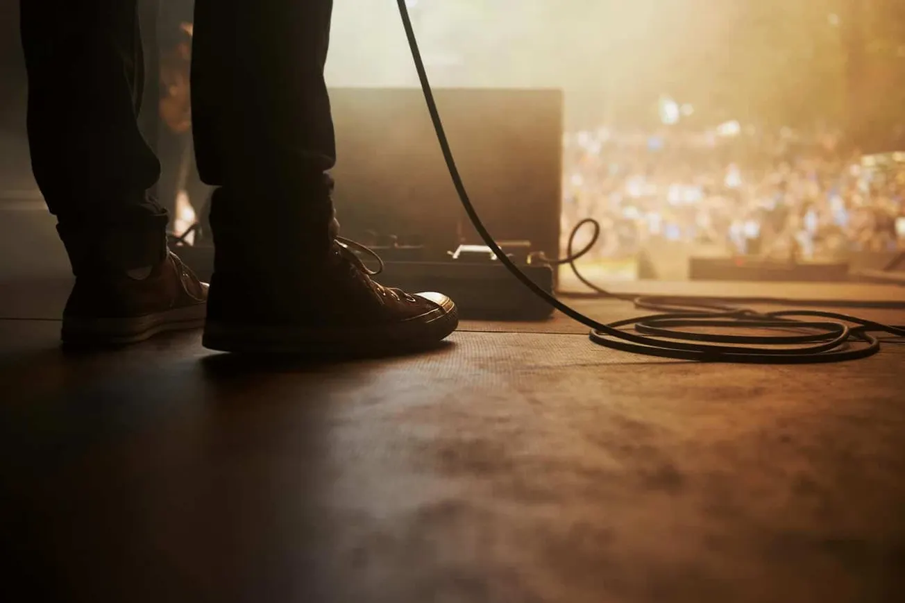 Studio musician performing live on stage with equipment in dim lighting, capturing a concert or music event for SEO-friendly