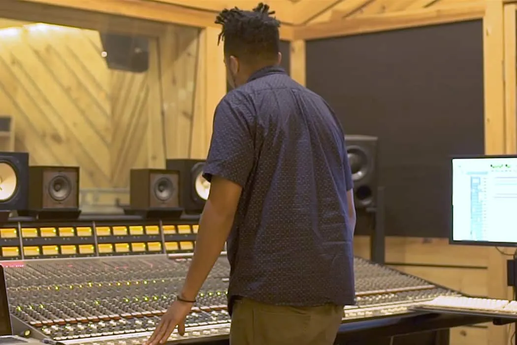 Professional music producer working in a recording studio with sound mixing console, studio monitors, and digital audio works