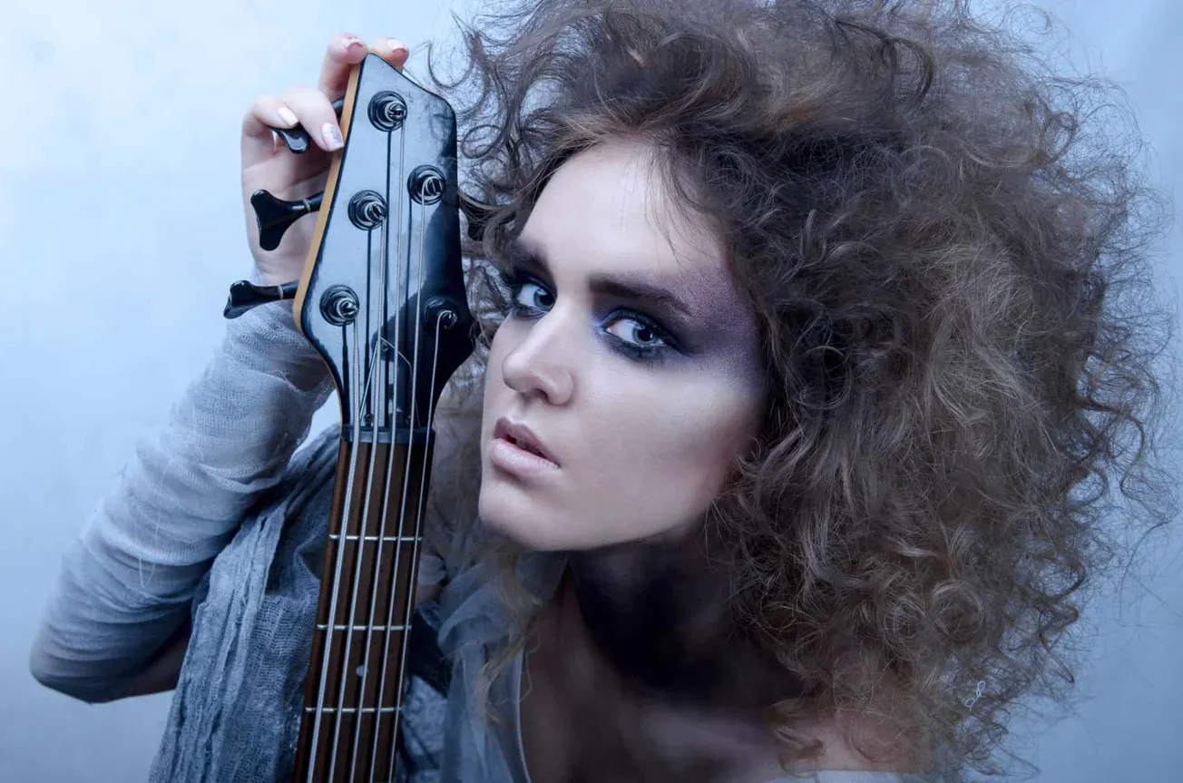 Vibrant image of a woman with curly hair holding a guitar headstock, showcasing modern music aesthetics and artistic expressi