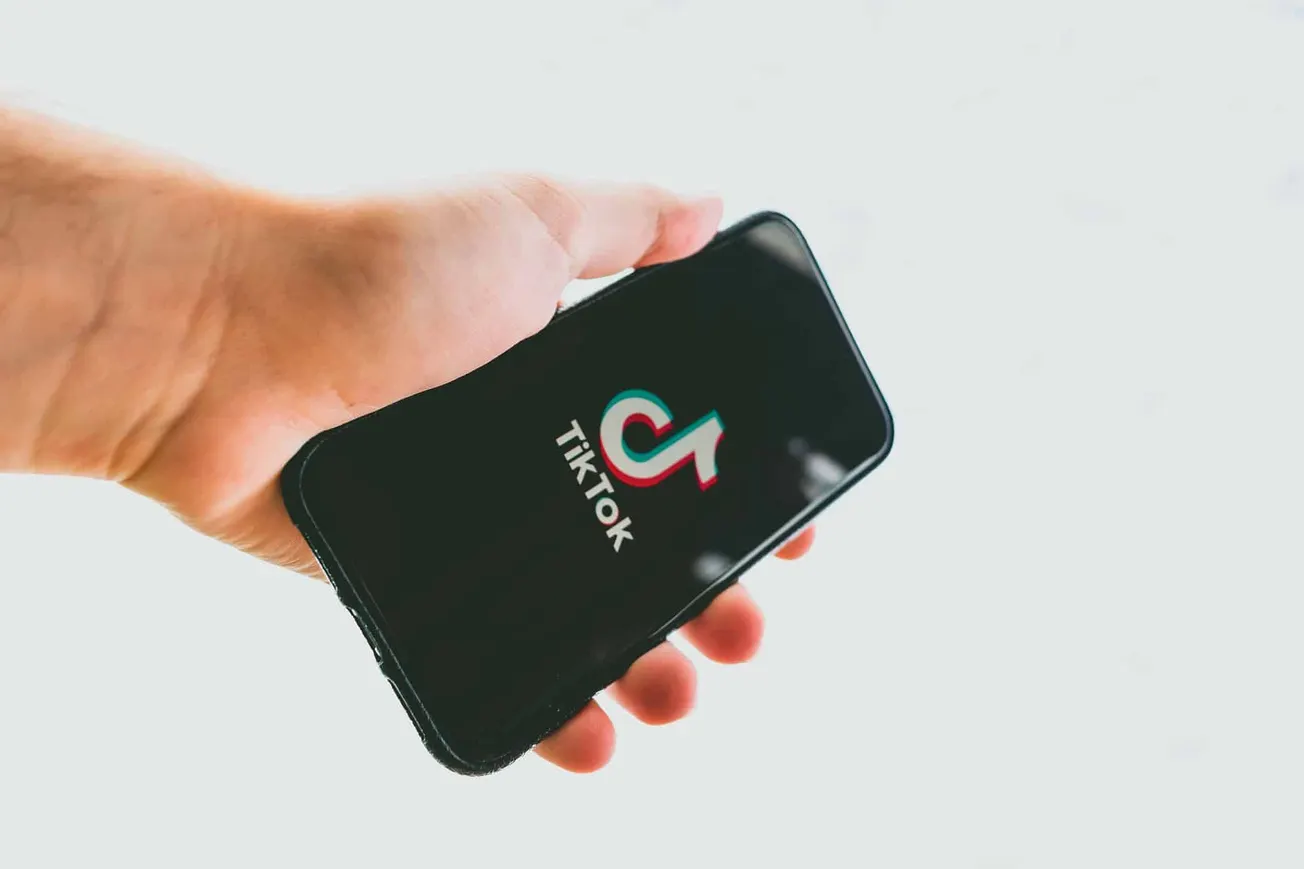 TikTok app logo on a smartphone screen in a hand, representing social media, digital marketing, and content creation.
